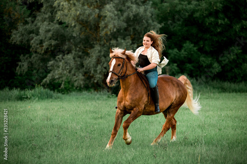 Girl fast ride horse in field in farm on sunset. forest on background
