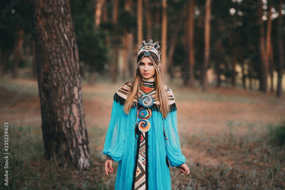 Beautiful girl in a blue Indian suit with feathers on her head.