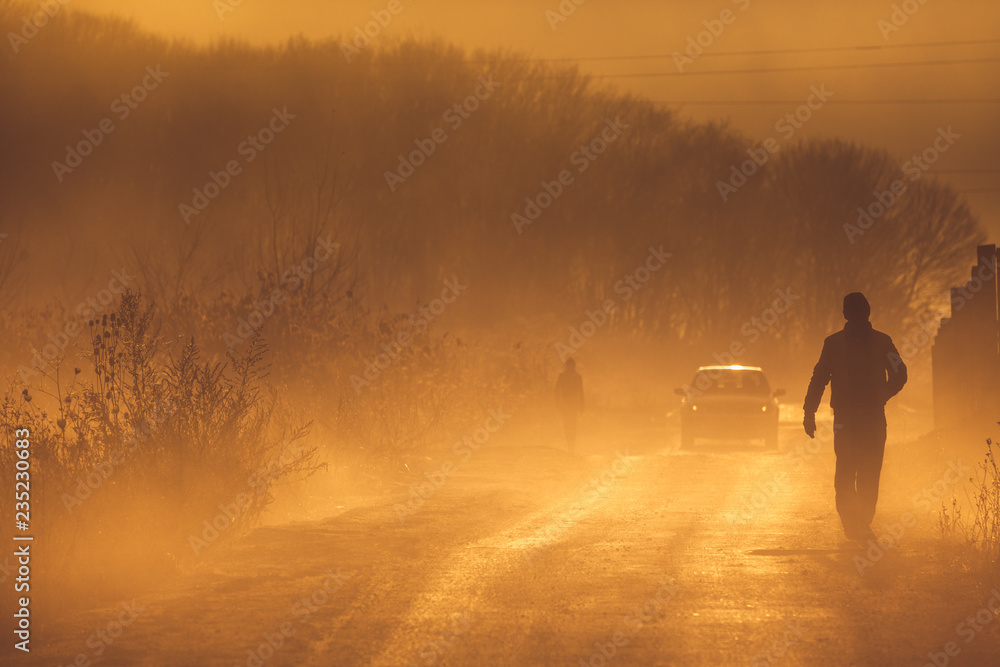 Morning walk in rural area filled with orange smoke