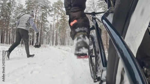 Action cam on frame installed behind. Close-up pov view. Professional extreme sportsman biker riding fat bike in outdoors in winter snow forest. photo