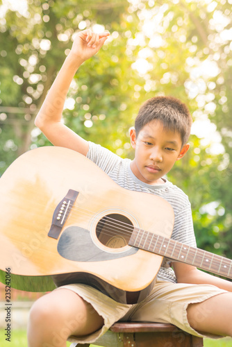 The boy playing guitar in the garden in the sunset light