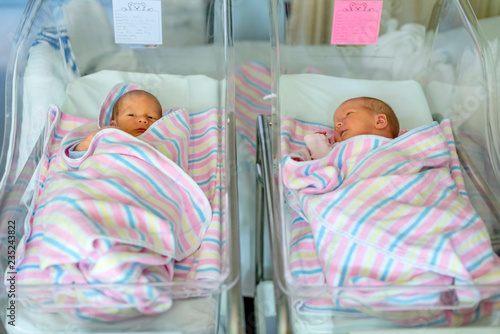 newborn twins boy and girl in hospital under blankets