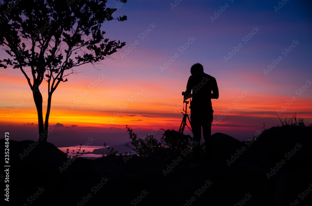 Silhouette Young man photographer taking nature photo on PhraYa Dern Thong mountain landscape.province Lopburi.Thailand. tourist photographe shooting dslr camera on tripod