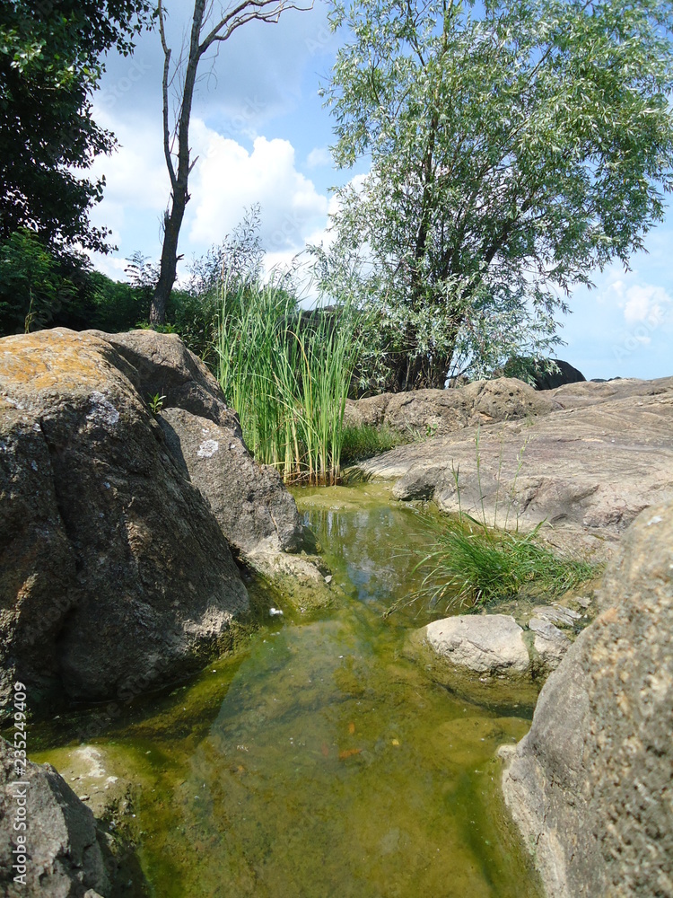 Water stands between large stones. Dnepr River. Summer sunny day. Ukraine.