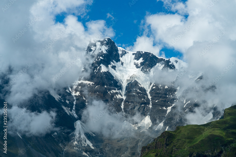 Ancient towering snow capped peaks of the might Himalaya rising into fluffy white clouds  