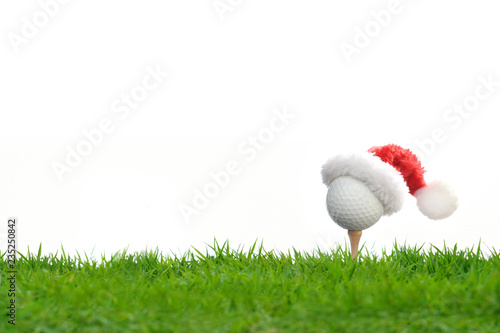 Festive-looking golf ball on tee with Santa Claus' hat on top for holiday season isolated on white background
