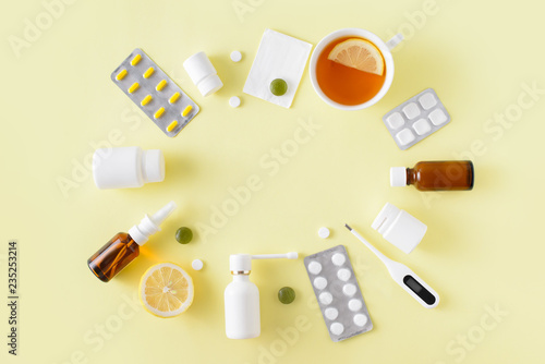 Cold and flu treatment set. Pills, throat spray, medical mask, thermometer, recipe on simple yellow background. Health care therapy. Flat lay, top view. Frame with free copy space.