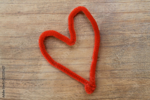 Red heart pipe cleaner on wood background