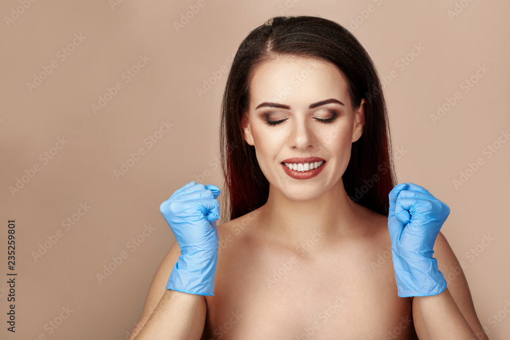 Portrait of upset young woman showing hands in latex gloves, beige or light brown background Portrait of upset young woman showing hands in latex gloves, beige or light brown background