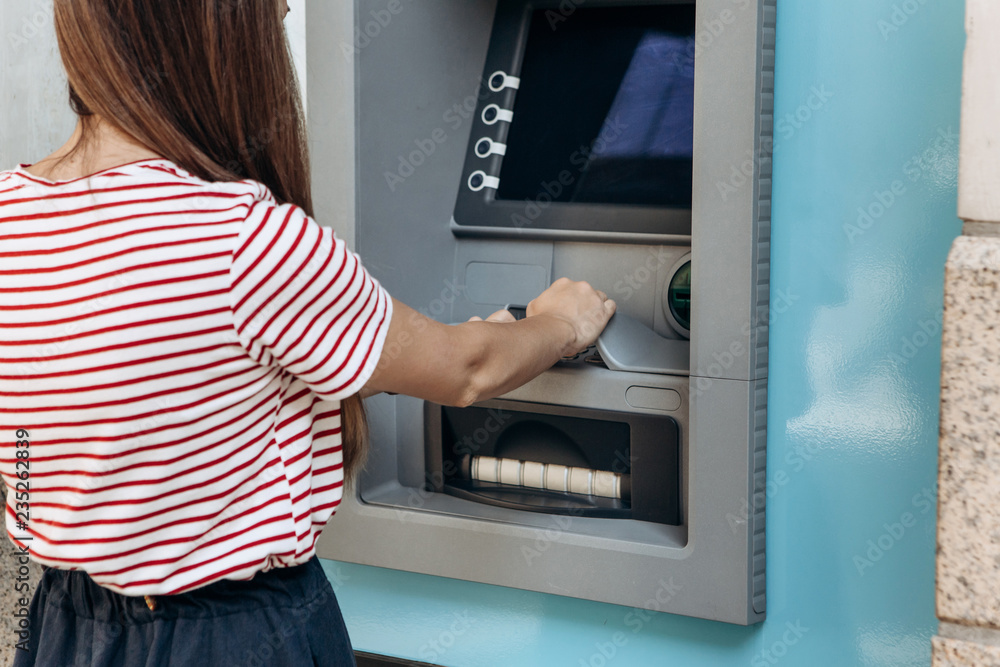 The tourist withdraws money from the ATM for further travel. Finance, credit card, withdrawal of money. Life style. Journey. Vacation. Grabs a card from the ATM. The tourist withdraws money from the ATM for further travel. Finance, credit card, withdrawal of money. Life style. Journey. Vacation. Grabs a card from the ATM.