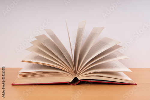 Photography open hardcover book with turning pages in fan shape on desk