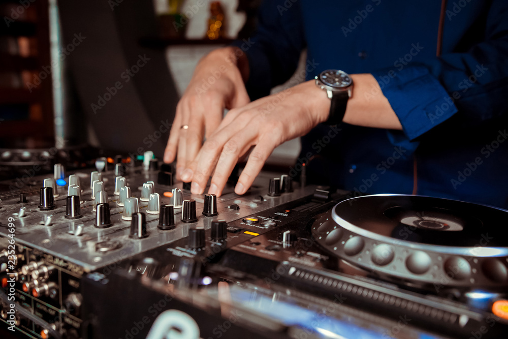 DJ Spinning, Mixing, and Scratching in a Night Club, Hands of dj tweak various track controls on dj DJ Spinning, Mixing, and Scratching in a Night Club, Hands of dj tweak various track controls on dj