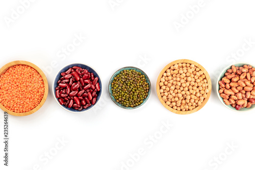Various types of legumes, shot from the top on a white background with a place for text. Red kidney and pinto beans, lentils, chickpeas, soybeans with copy space