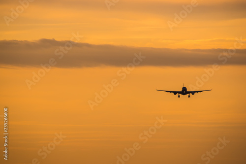 Dramatic view of a dark silhouette of aircraft against a orange sunset sky © Media_Works