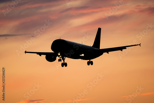 Dramatic view of a dark silhouette of aircraft against a orange sunset sky