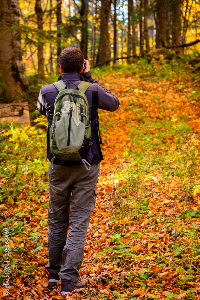 Back view male photographer in bright autumn forest