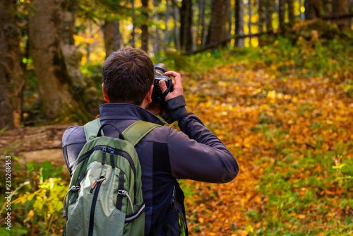 Obraz na płótnie Back view male photographer in bright autumn forest w salonie