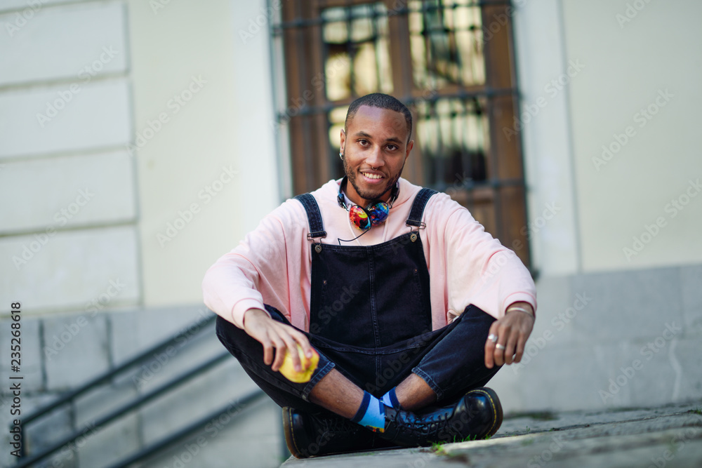 Young black man eating an apple sitting on urban steps. Stock Photo ...