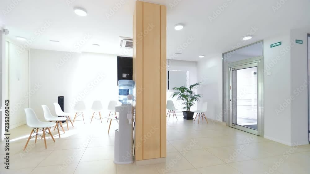 Panorama of a bright reception and waiting room in a clinic with desk, modern chairs and plants. Panorama of a bright reception and waiting room in a clinic with desk, modern chairs and plants.
