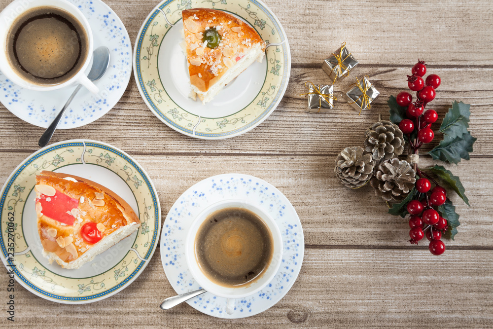 Two cut pieces of Spanish typical dessert of epiphany with coffee and mistletoe Two cut pieces of Spanish typical dessert of epiphany with coffee and mistletoe