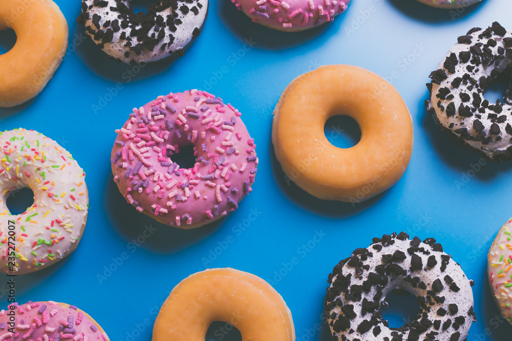 Top view of many colorful donuts on blue background. Top view of many colorful donuts on blue background.