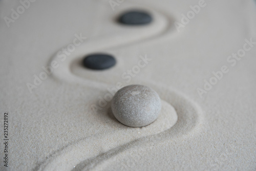 Gray zen stones on the sand with wave drawings. Concept of harmony, balance and meditation, spa, massage, relax