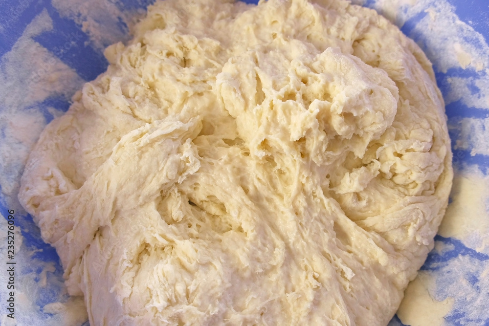 Preparation of yeast dough in a blue plastic bowl. Close-up view. Preparation of yeast dough in a blue plastic bowl. Close-up view.