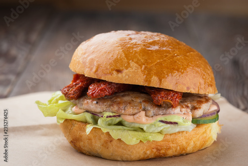 Homemade cheese burger or hamburger on brown paper put on wood table with copy space. Fast food for breakfast or lunch. Hamburger with dried tomatoes