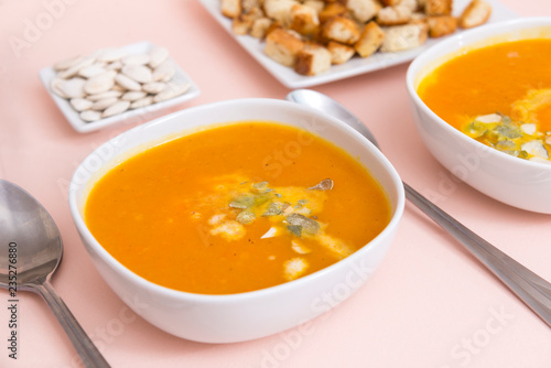 orange pumpkin soup in plates, spoons, vegetable soup