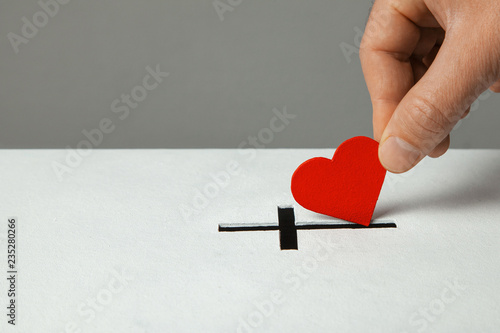 Donation of your heart as symbol of love for the religion of Christianity. Box for donations with slot in the form of Christian christe. Man puts hand donations. Copy space for text