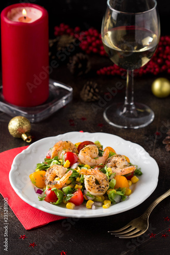 Salad with corn, fried shrimp, cherry tomatoes, red onions and lettuce on white plate. Appetizer for Christmas party