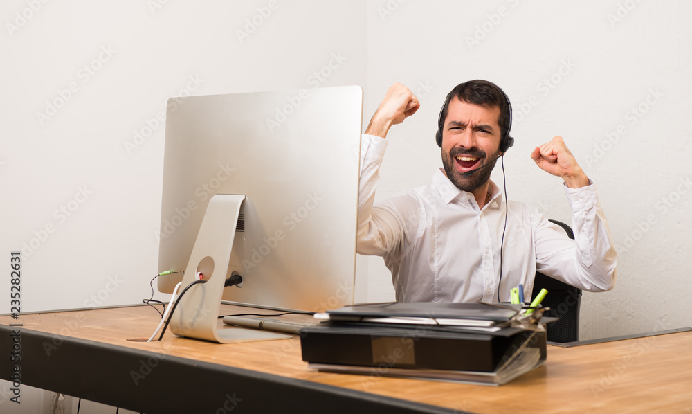 Telemarketer man in a office celebrating a victory in winner position Telemarketer man in a office celebrating a victory in winner position