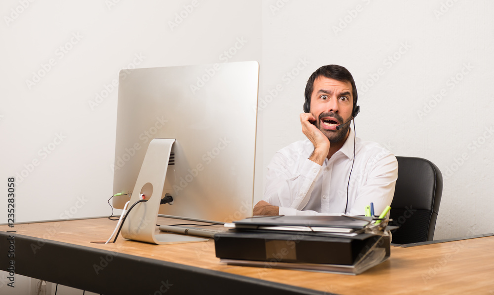 Telemarketer man in a office surprised and shocked while looking right Telemarketer man in a office surprised and shocked while looking right