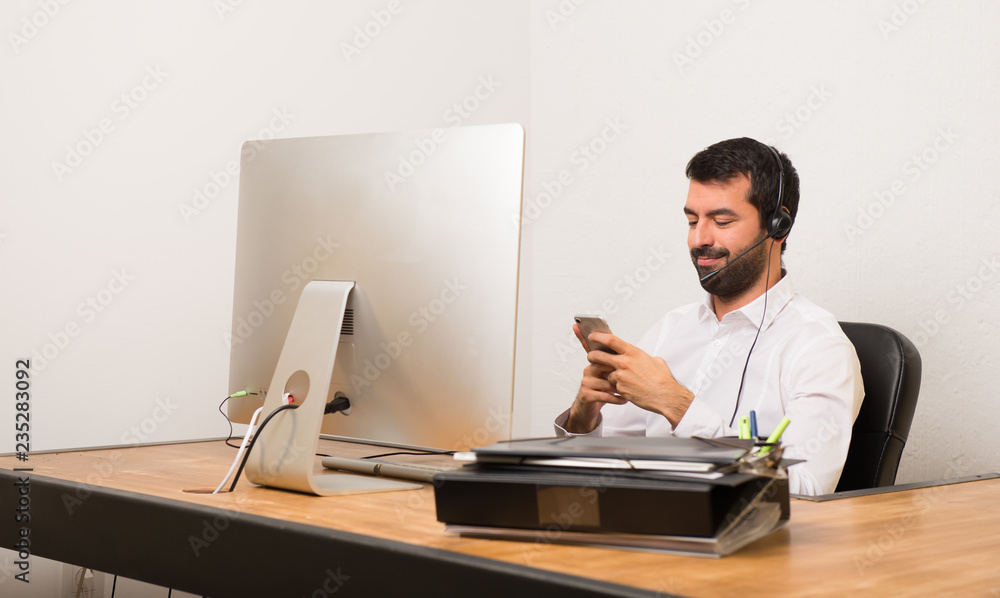 Telemarketer man in a office talking to mobile Telemarketer man in a office talking to mobile