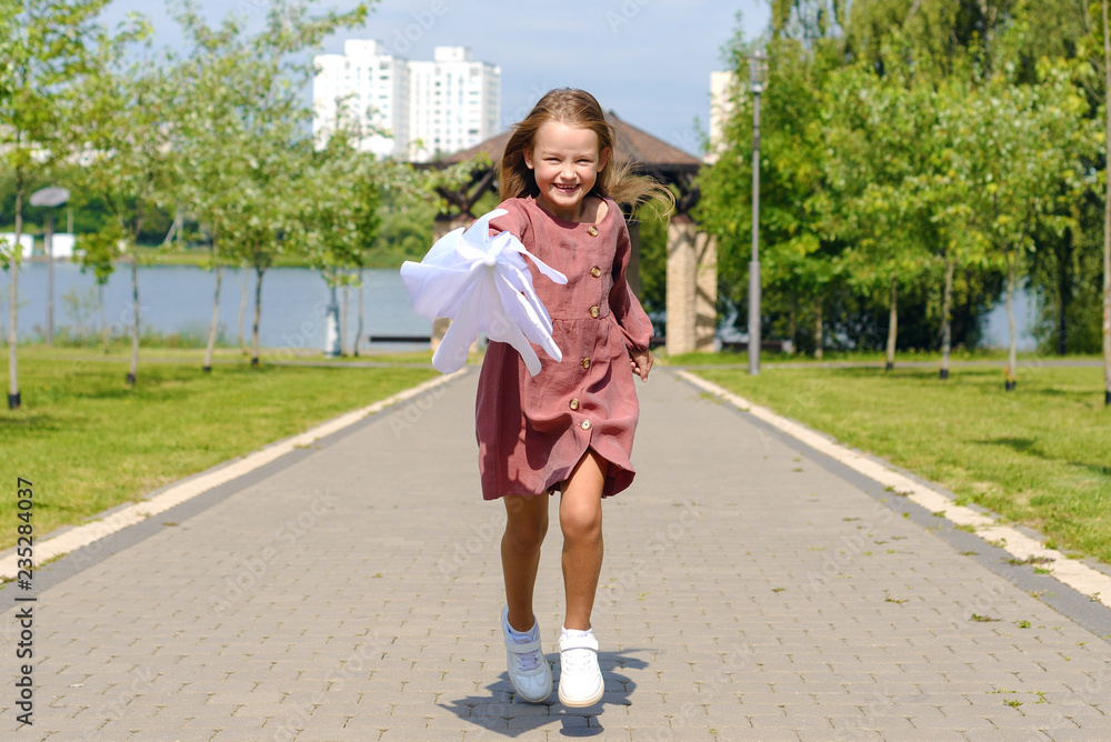 cute happy little girl in burgundy dress running with white umbrella
