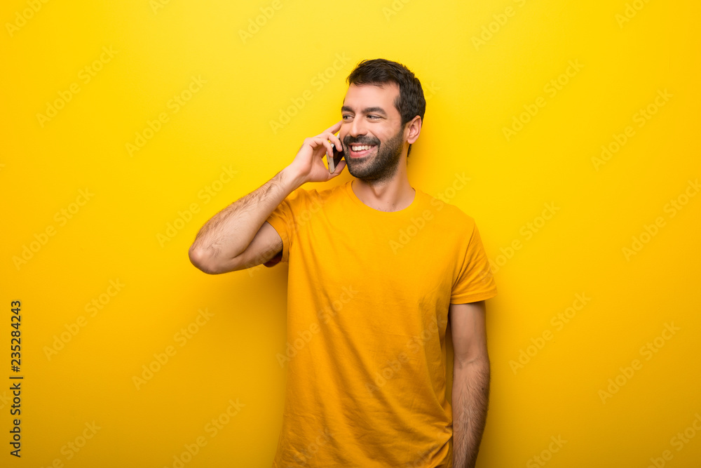Man on isolated vibrant yellow color keeping a conversation with the mobile phone with someone Man on isolated vibrant yellow color keeping a conversation with the mobile phone with someone