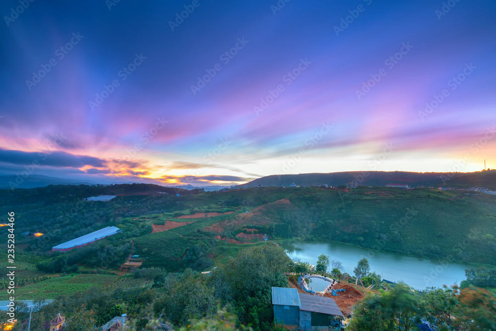 Dawn on plateau in morning with colorful sky, while sun rising from horizon shines down to small village landscape so beautiful idyllic countryside Dalat plateau, Vietnam