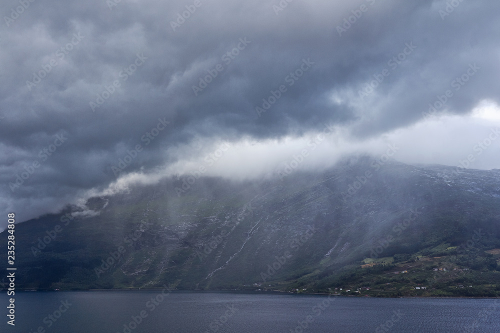 Wolken regnen sich auf anderer Fjordseite ab
