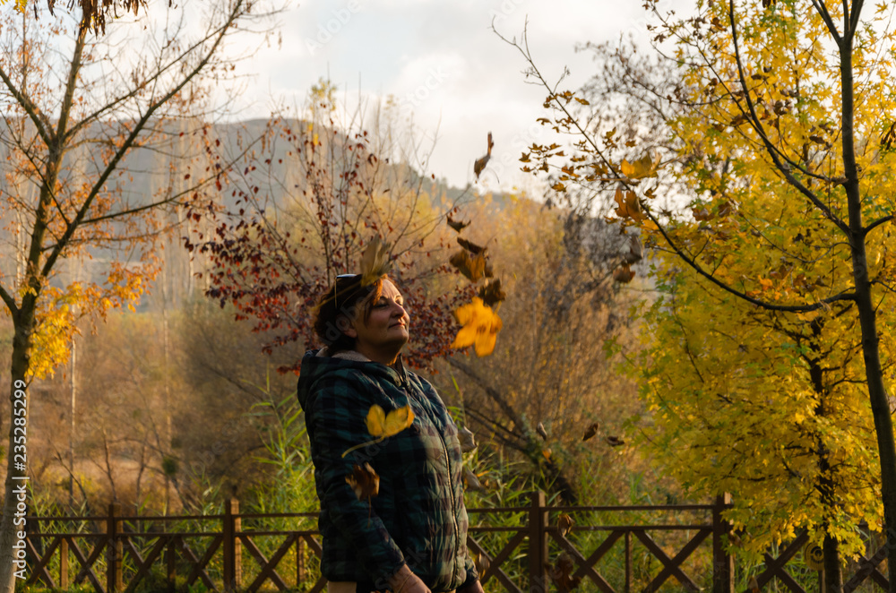 Naklejka premium Senior woman is standing among fallen leaves in autumn