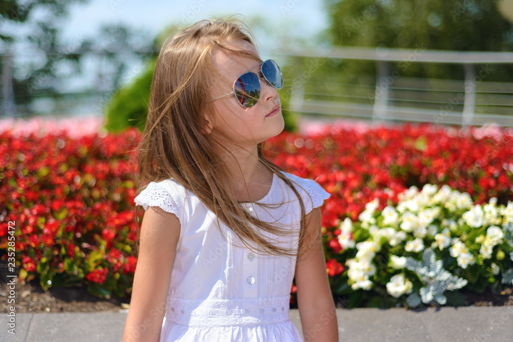 Portrait of little girl in white dress wearing sunglasses. Portrait of little girl in white dress wearing sunglasses.