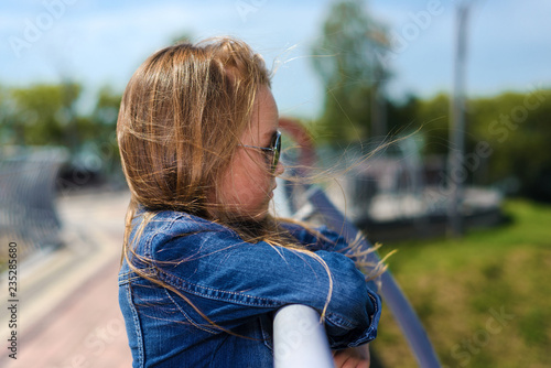 portrait of beautiful little girl inwhite dress in blue denim jacket and sunglasses photo