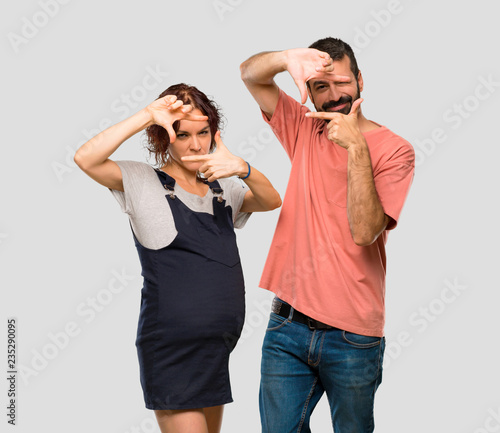 Couple with pregnant woman focusing face. Framing symbol on isolated grey background