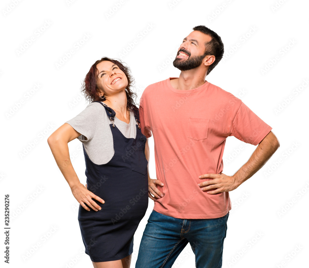 Couple with pregnant woman posing with arms at hip and laughing on isolated white background Couple with pregnant woman posing with arms at hip and laughing on isolated white background