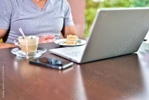 Young guy freelancer working on laptop in cafe