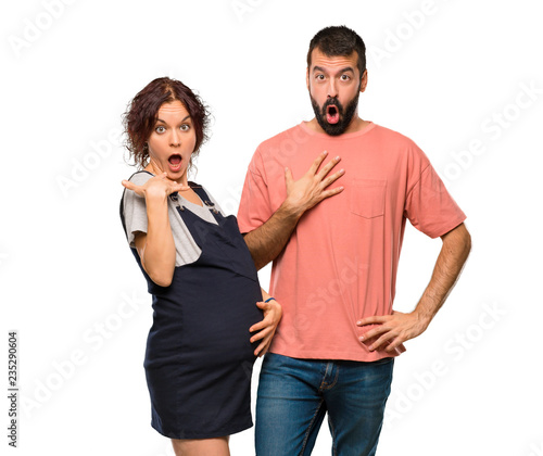 Couple with pregnant woman surprised and shocked. Expressive facial emotion on isolated white background