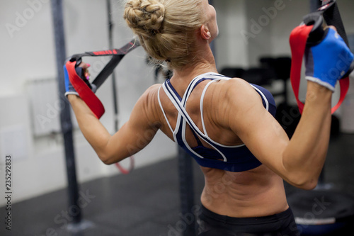 A sexy woman trains in the gym. Athletic woman trains with dumbbells, pumping her biceps