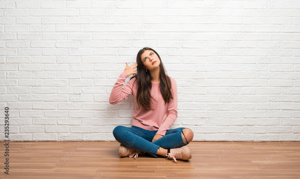 Teenager girl sitting on the floor in a room with problems making suicide gesture Teenager girl sitting on the floor in a room with problems making suicide gesture