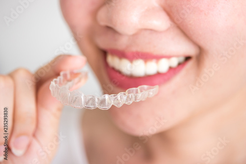 A smiling woman holding invisalign or invisible braces, orthodontic equipment