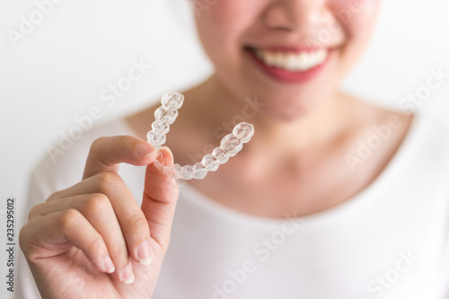 A smiling woman holding invisalign or invisible braces, orthodontic equipment