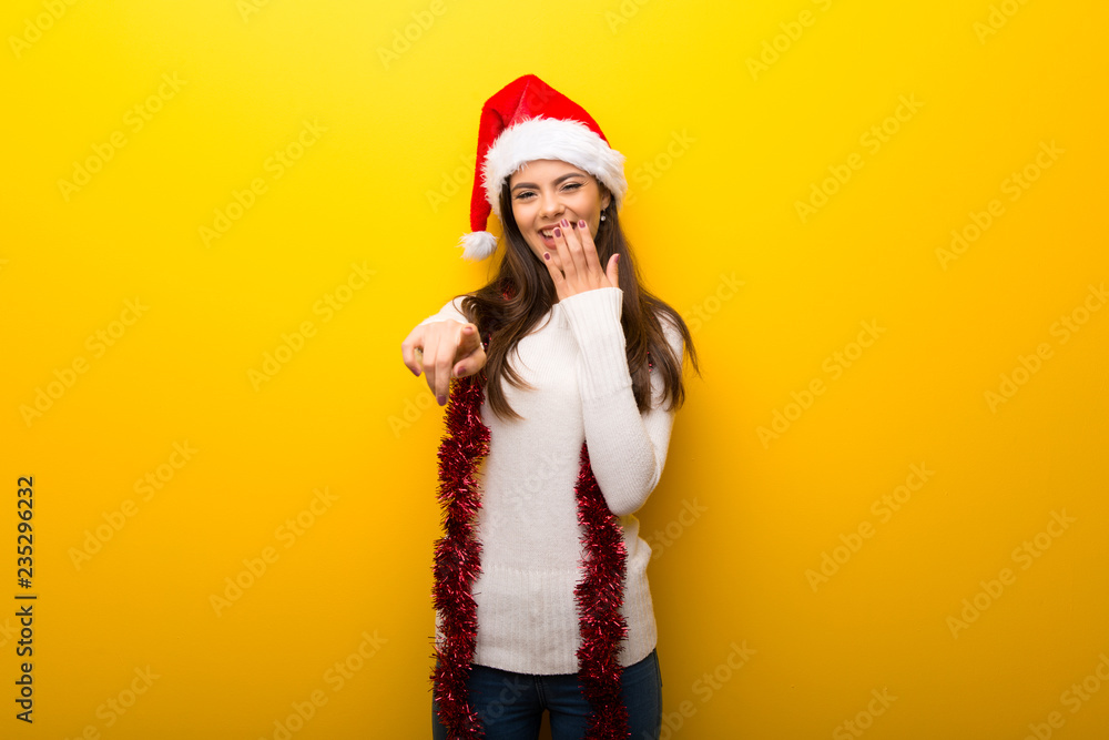 Teenager girl celebrating christmas holidays pointing with finger at someone and laughing a lot
